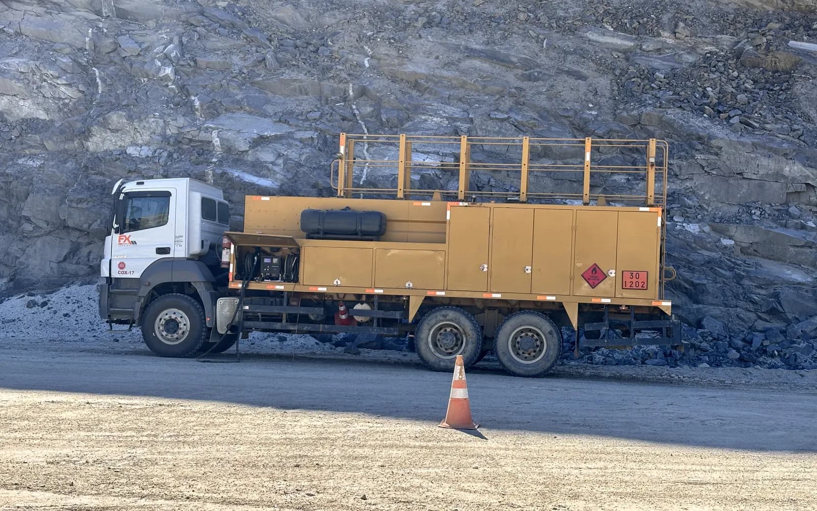 Caminhão comboio lubrificador com a marca FX Minas parado diante da parede da cava: a manutenção que vai até a frente para segurar a disponibilidade física da frota